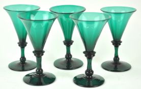 A set of five early 19th century green wine glasses, each with flared bowls,