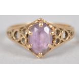 A yellow metal single stone ring. Set with an oval faceted cut pale amethyst.