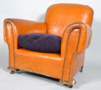 A club armchair, upholstered in tan leather with drop in purple velvet cushion, with studwork arms,