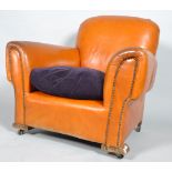 A club armchair, upholstered in tan leather with drop in purple velvet cushion, with studwork arms,