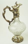 A cut glass claret jug with Rococo silver plated mounts, decorated with 'C' scrolls and flowers