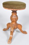 A Victorian revolving piano stool, the carved oak baluster support on three carved cabriole legs,