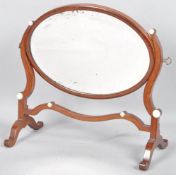 A George III mahogany oval swing frame dressing table mirror, the cushion shaped frame,