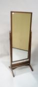 An oak framed rectangular cheval mirror on a plain stand with brass urn finials, 160cm high,