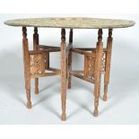 An eastern brass tray table on foldable teak stand the table with petal- shaped central well