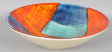 A Poole pottery gemstone centre bowl, decorated in typical palette on an orange ground,