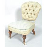 A Victorian button back nursing chair on turned mahogany legs on brass and ceramic casters,