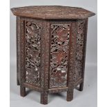 A teak occasional table of octagonal section with chip-carved top with continuous fruiting vine,