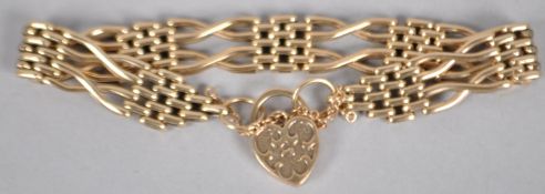 A yellow metal gate and brick link bracelet finished with a fancy heart shaped padlock clasp.