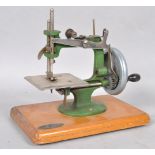 A mid 20th century "Grain" Mark I miniature sewing machine, on wooden plinth base,