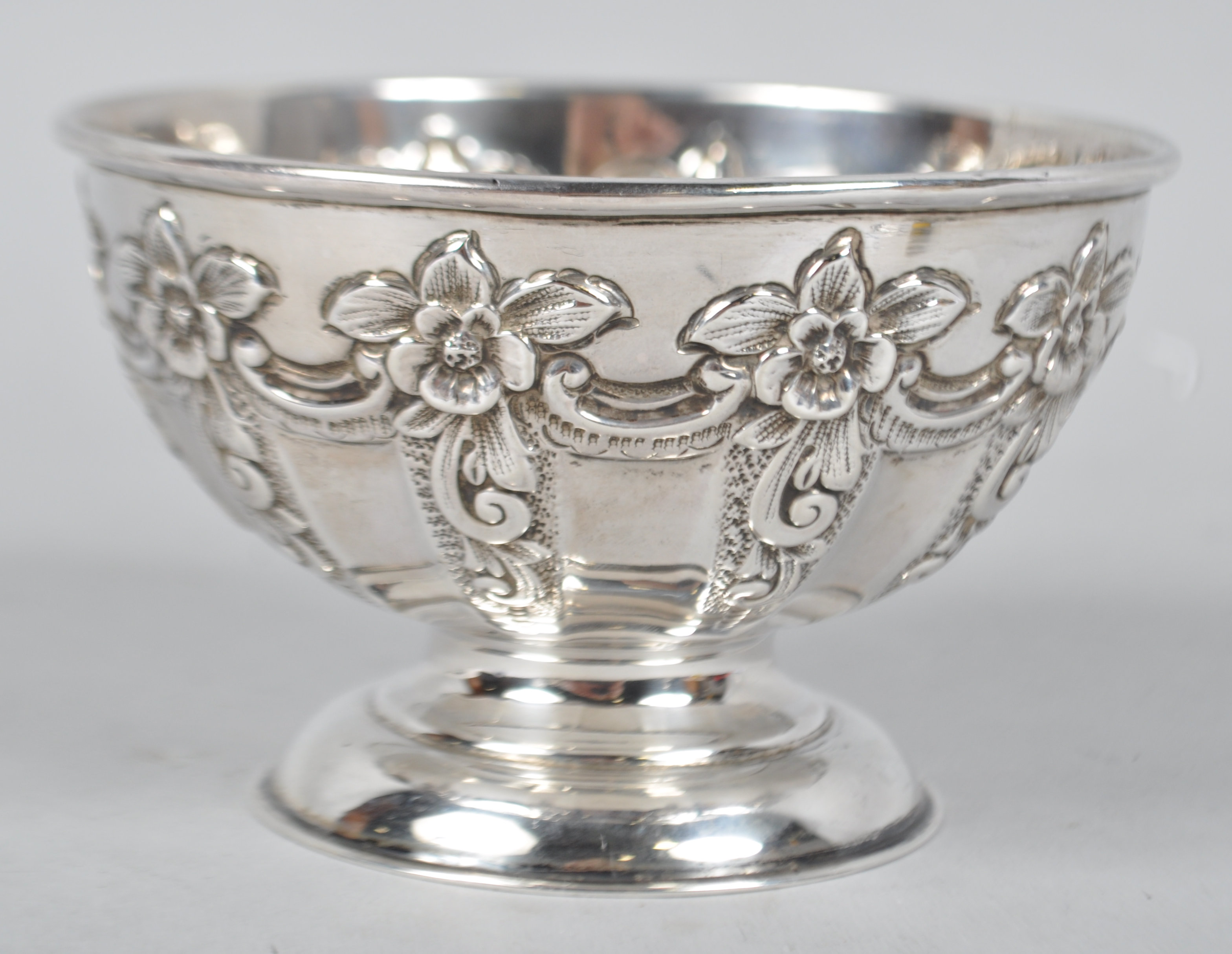 A silver hemispherical bowl decorated with repousse rococo panels and raised on a plain foot