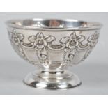 A silver hemispherical bowl decorated with repousse rococo panels and raised on a plain foot