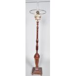 An oil lamp with mottled glass reservoir raised on a mahogany baluster turned stem on a satinwood