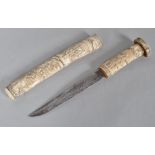 An Oriental Tauto the bone scabbard and grip carved with a cascade of figures,