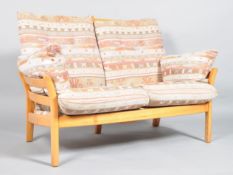 An Ercol Saville light elm two seater sofa, with high slatted back and sides,