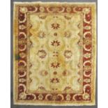 A wool carpet with beige ground woven with scrolling leaves and flowerheads in yellow, red and blue,