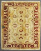 A wool carpet with beige ground woven with scrolling leaves and flowerheads in yellow, red and blue,