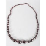 A vintage ruby amber necklace, the graduated faceted oval beads on knotted ruby thread,