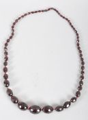 A vintage ruby amber necklace, the graduated faceted oval beads on knotted ruby thread,