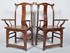 A pair of Chinese carved huanghuai yoke back armchairs with arched top rails and handles,