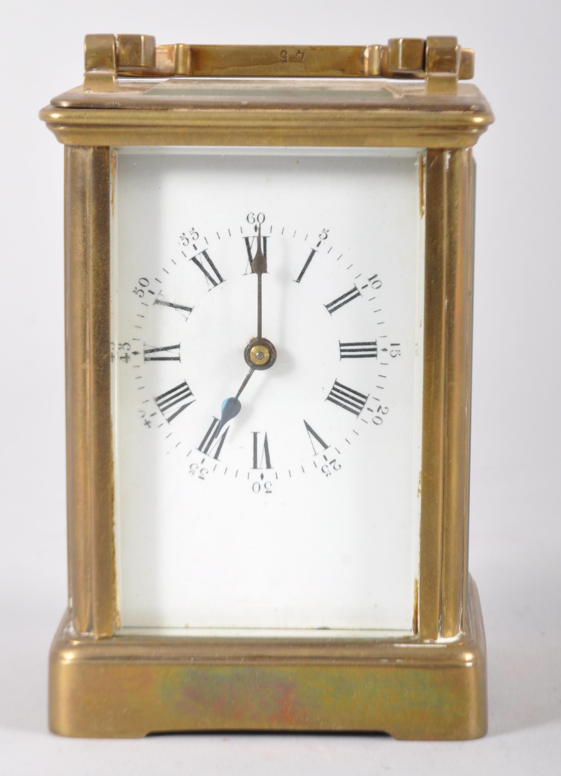 A French brass framed carriage clock, 20th century, with white enamel dial and brass swing handle,