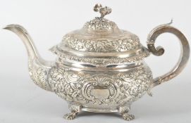 An Irish silver teapot, of heavily repousse decorated floral and scroll round form,