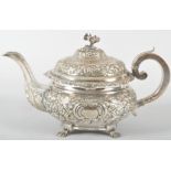 An Irish silver teapot, of heavily repousse decorated floral and scroll round form,