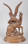A Continental carved wooden sculpture of an eagle attacking a goat,