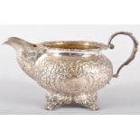 An Irish silver milk jug, of heavily repousse decorated floral scroll round form,