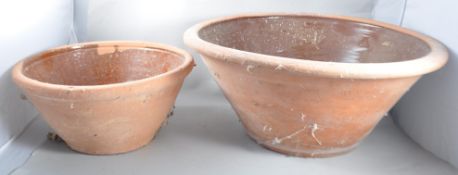 A set of two graduating terracotta dairy bowls of usual form having a salt glazed inner and