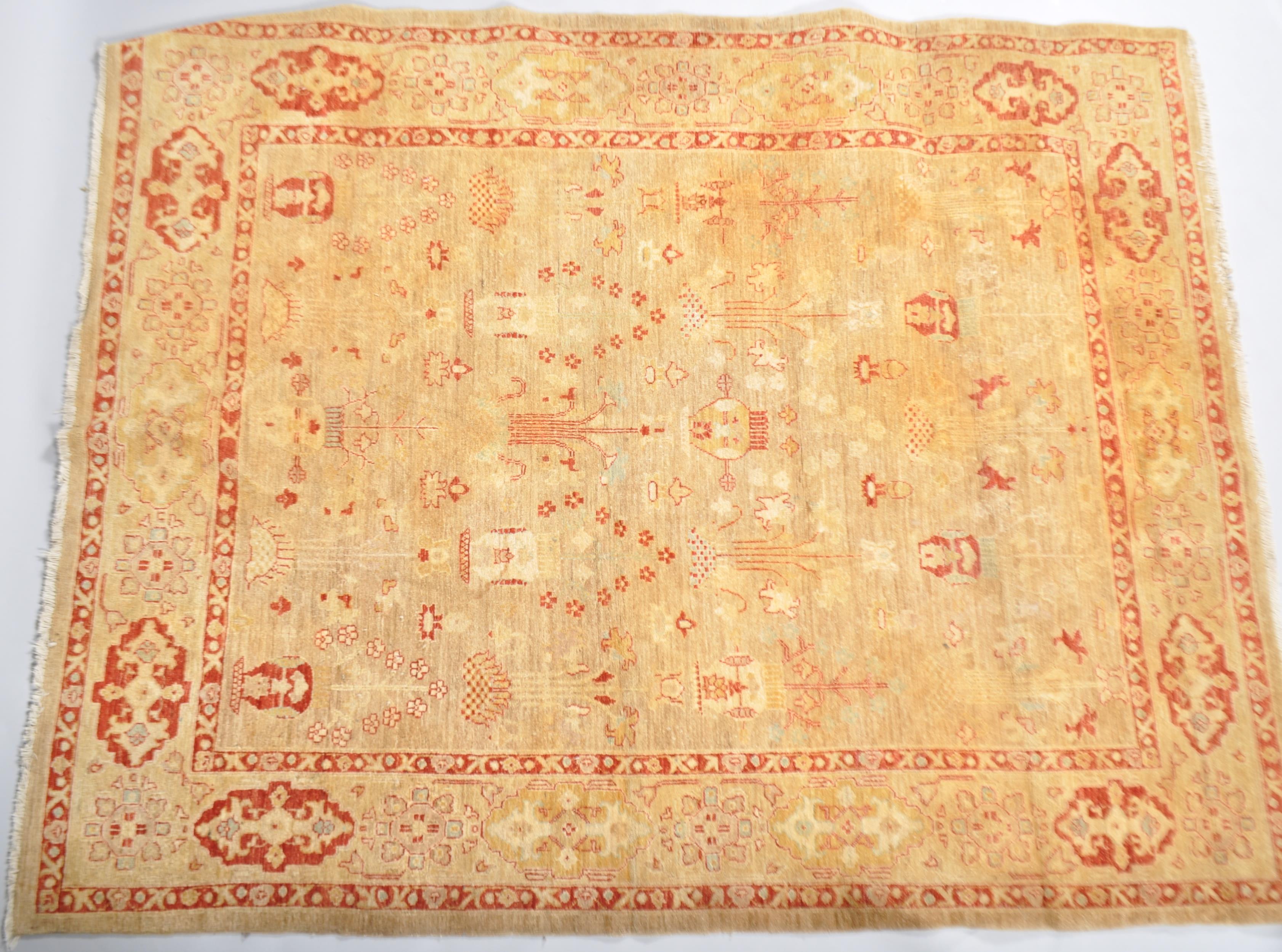 A wool carpet with pale brown ground woven with red jardinieres of flowers,