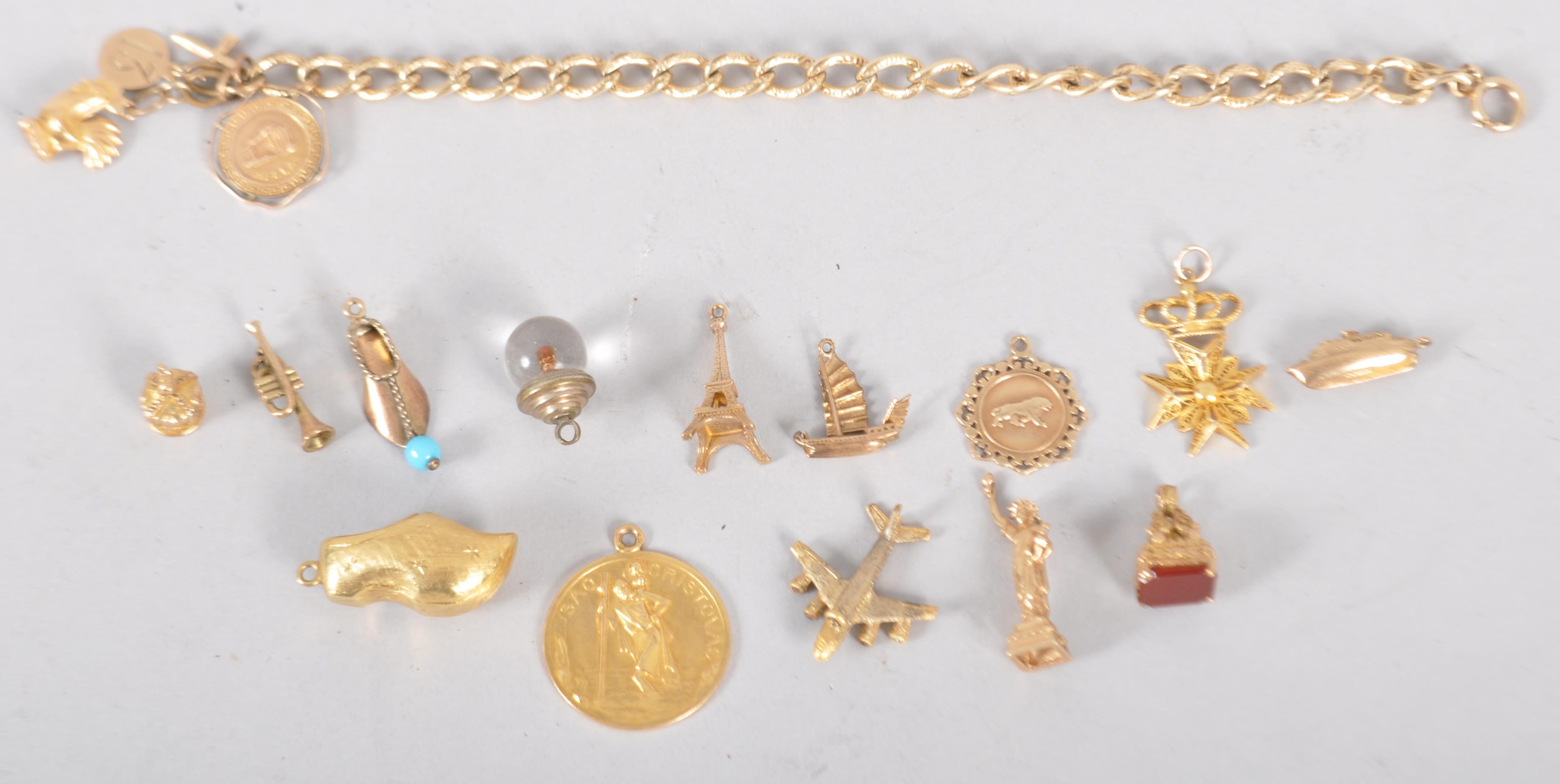 A yellow metal curb link bracelet having four fixed charms and fourteen assorted loose charms. - Image 4 of 6