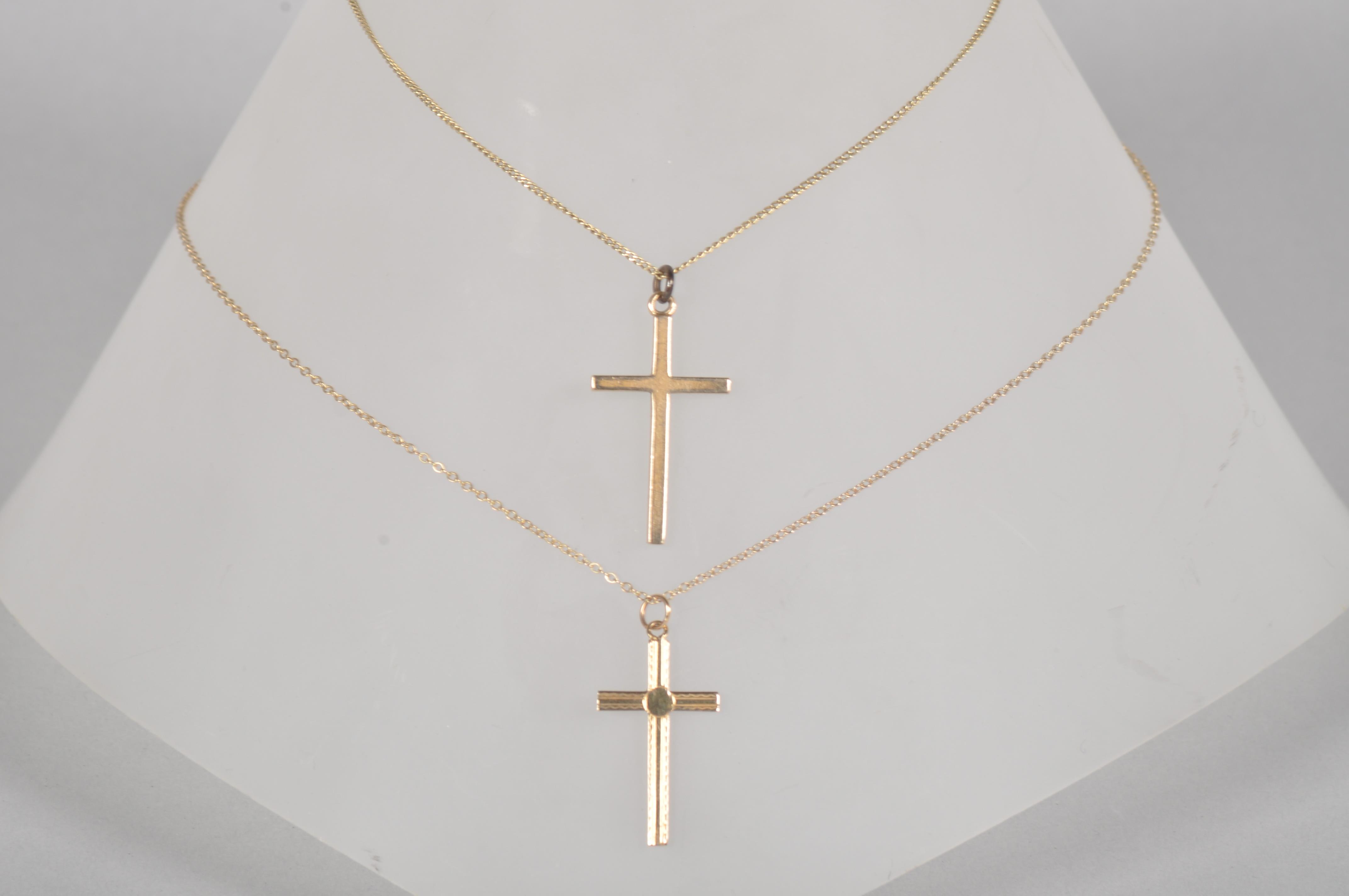 A collection of two cross pendants with chains.