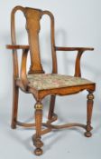 A George II style mahogany and walnut armchair, with vase-shaped splay before scroll arms,