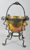 A brass coal bucket on cast iron stand, with spiral handle, on scroll bracket supports and legs,