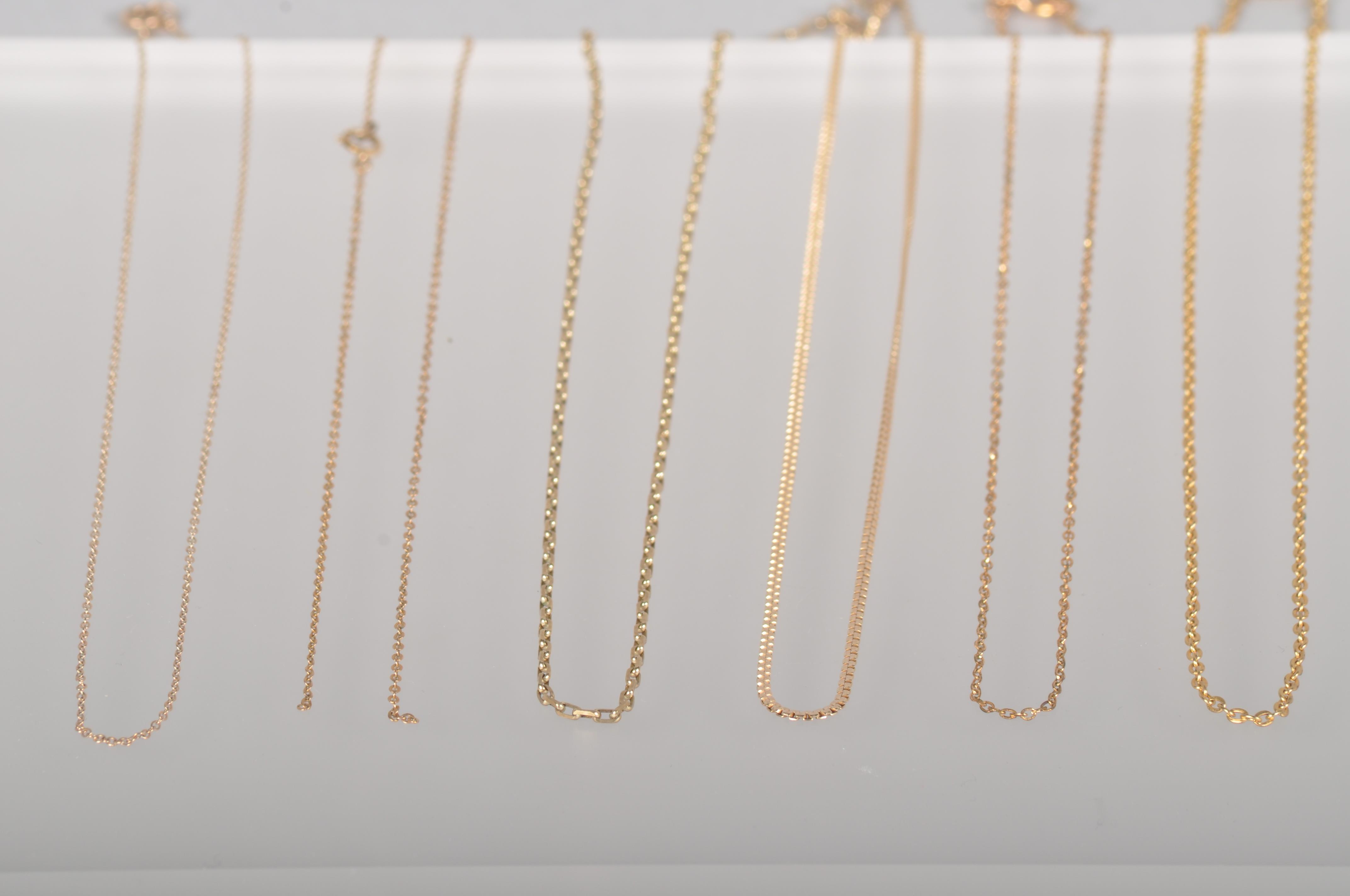 A collection of six yellow metal linked necklace chains.