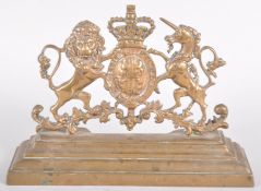 A brass fire surround mount cast with the Royal Arms, on a stepped plinth base,