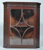 A George III style mahogany glazed corner cabinet, of canted form,