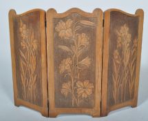 An Art Nouveau oak three section fire screen, with carved floral decoration,