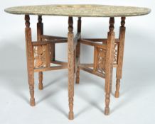 An eastern brass tray table on foldable teak stand the table with petal- shaped central well