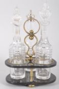 A Victorian brass mounted ebonised cruet stand and three cut glass cruet bottles,