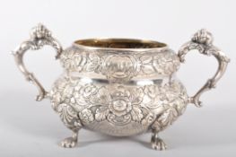 An Irish silver sugar bowl, of heavily repousse decorated floral banded form,