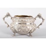 An Irish silver sugar bowl, of heavily repousse decorated floral banded form,