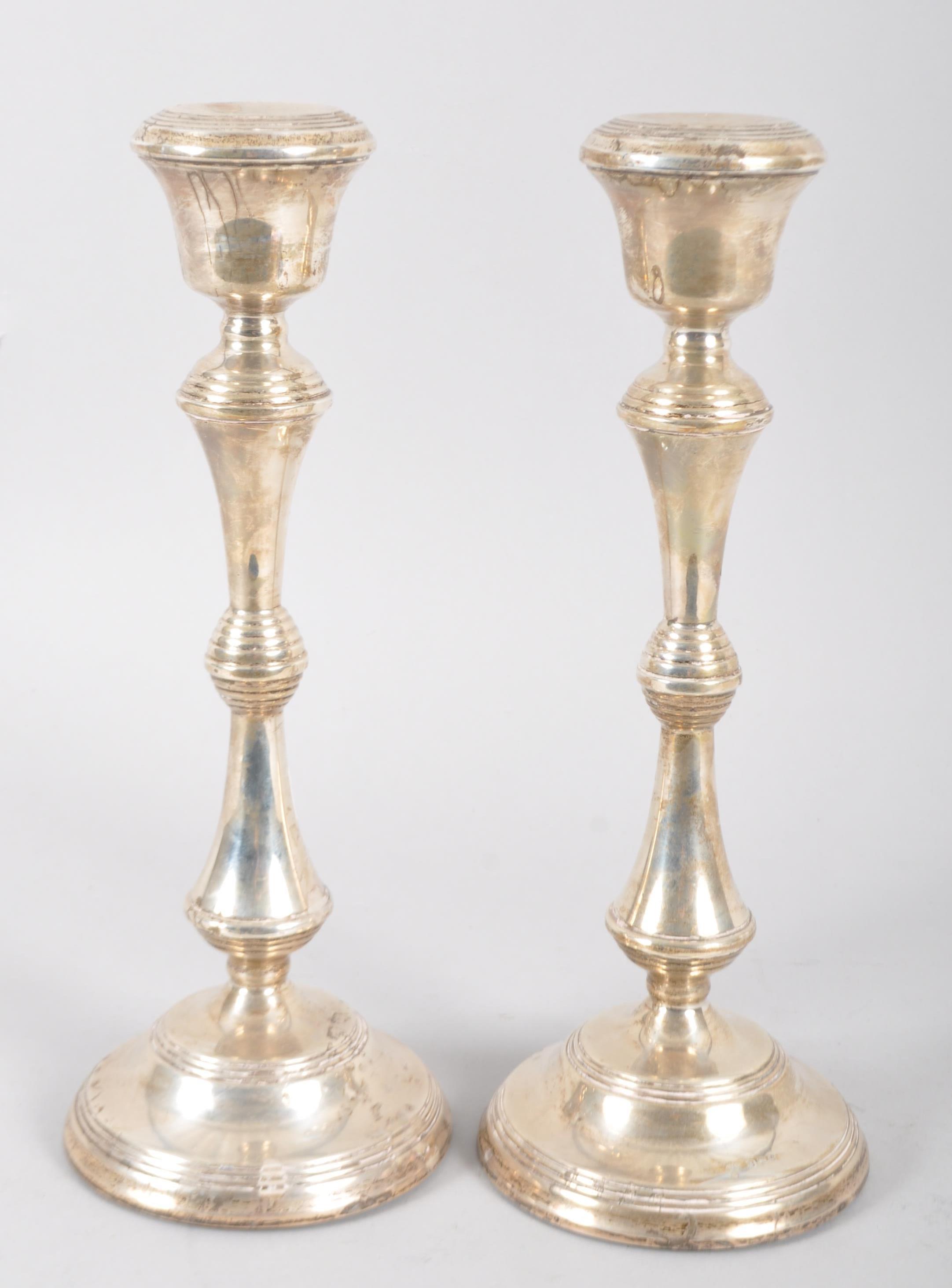 A pair of loaded silver candlesticks of traditional baluster form with reeded borders and inverted