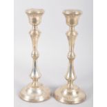 A pair of loaded silver candlesticks of traditional baluster form with reeded borders and inverted