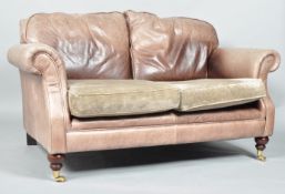 A Laura Ashley two seater leather sofa, upholstered in brown with scroll arms,