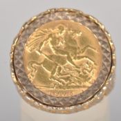 A yellow metal ring set with a half sovereign coin, dated 1905. Pierced shoulders with bark finish.