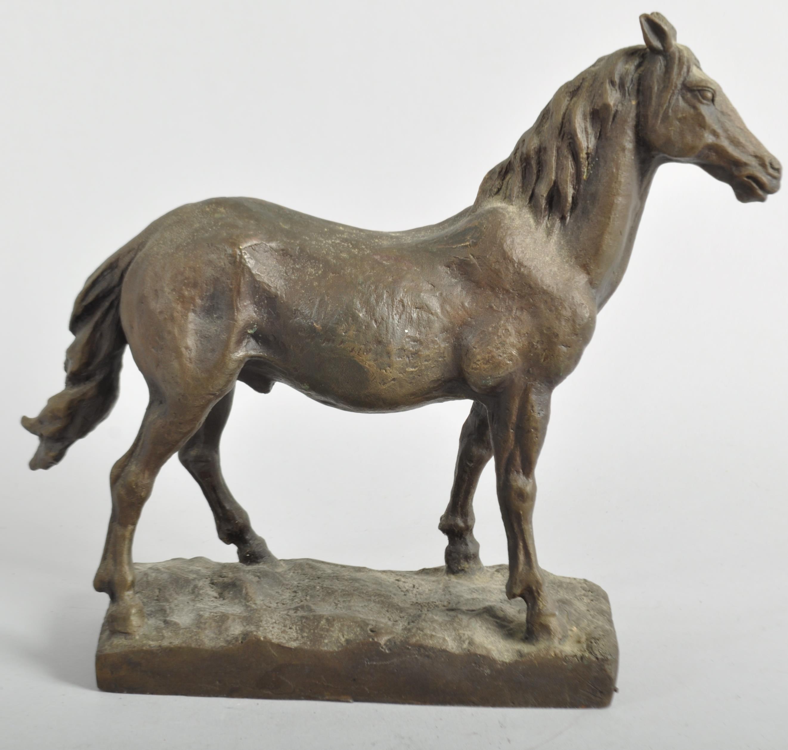 A bronze sculpture of a horse, naturalistically cast standing foresque on a rocky rectangular base,