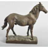 A bronze sculpture of a horse, naturalistically cast standing foresque on a rocky rectangular base,