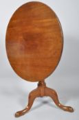 A mahogany tripod tilt-top tea table, with circular top above a baluster stem and tripod legs,